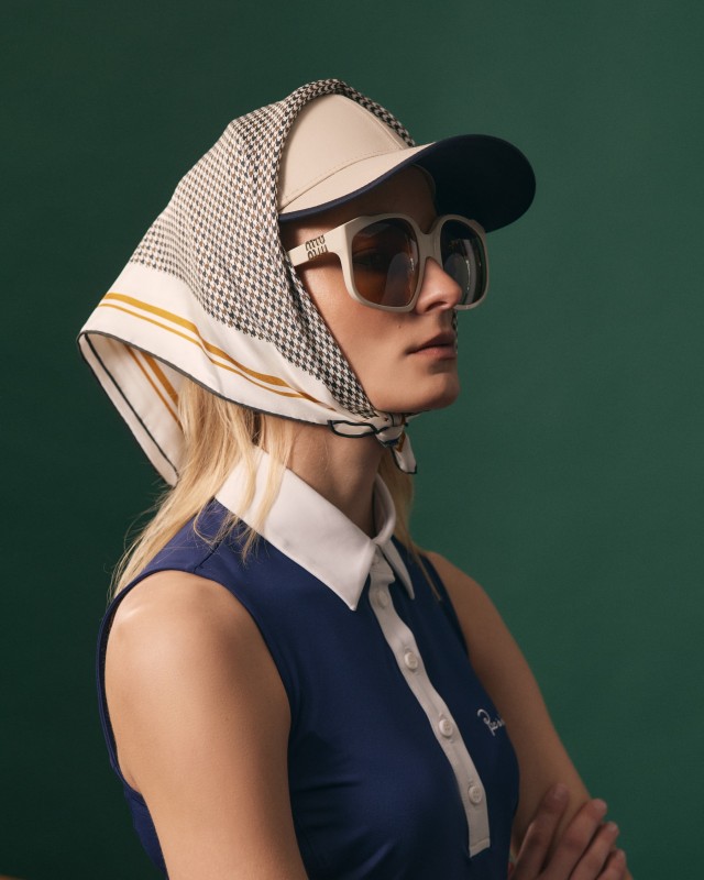 Modelka w czapce golfowej z jedwabną apaszką w pepitkę zawiązaną pod brodą