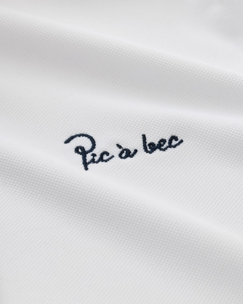 Zbliżenie haftowanego logo Pic à bec na białej tkaninie koszulki polo