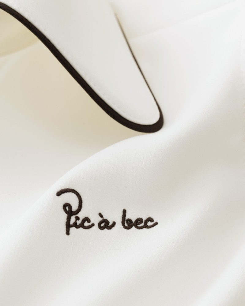 Zbliżenie na sukienkę polo z haftowanym logo Pic à bec, sukienka golfowa ecru