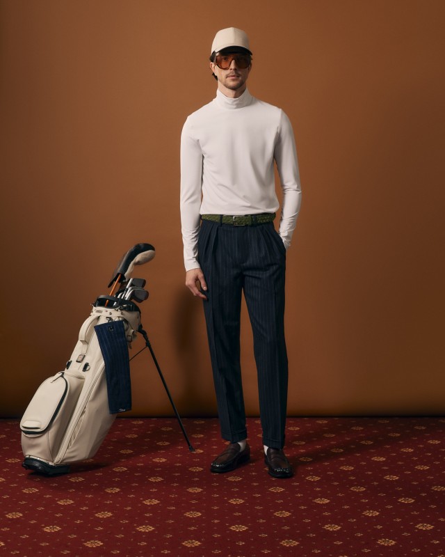 Męski golf z długim rękawem na modelu, obok zestaw kijów do golfa.